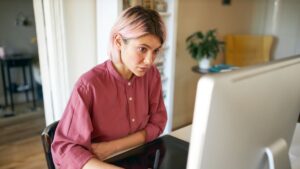 زن جوانی با تمرکز عمیق پشت لپتاپ در محیط کار، نمادی از زندگی بزرگسالان دارای اختلال طیف اتیسم و توانایی تمرکز بالا در فعالیتهای تخصصی